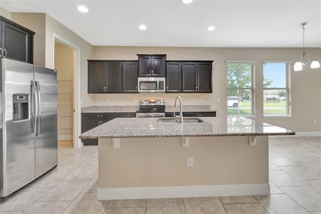 15531 Waterleigh Cove Dr, Winter Garden, FL 34787 - kitchen with appliances with stainless steel finishes, light stone countertops, a kitchen bar, light tile patterned floors, and a center island with sink
