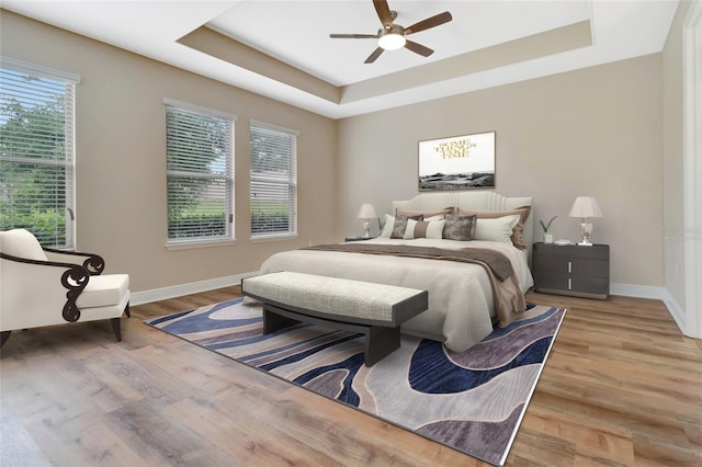 15531 Waterleigh Cove Dr, Winter Garden, FL 34787 - bedroom featuring a raised ceiling, light wood-type flooring, and ceiling fan