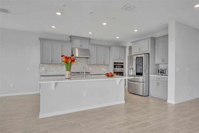 2147 Timber Creek Ln, Clermont, FL 34715 - kitchen with appliances with stainless steel finishes, gray cabinetry, light countertops, under cabinet range hood, and decorative backsplash