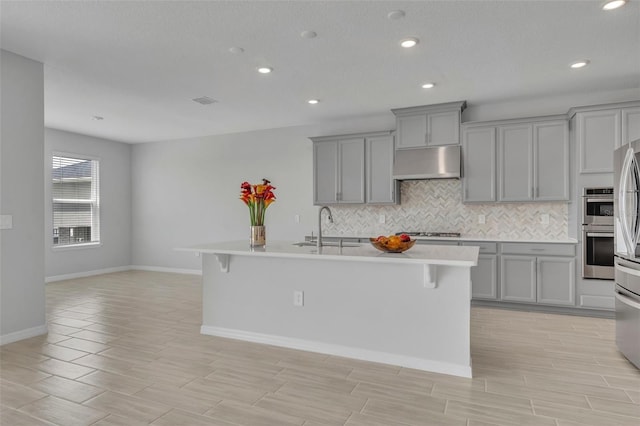 2147 Timber Creek Ln, Clermont, FL 34715 - kitchen with gray cabinetry, under cabinet range hood, a sink, decorative backsplash, and double oven