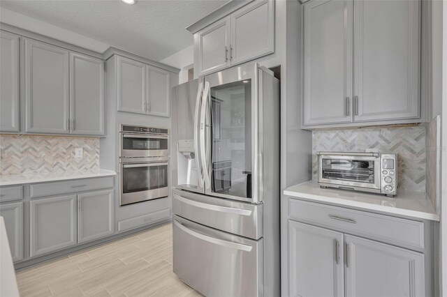 2147 Timber Creek Ln, Clermont, FL 34715 - kitchen featuring stainless steel appliances, gray cabinetry, decorative backsplash, light countertops, and light wood-style flooring