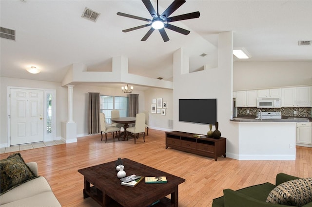832 Willow Run St, Minneola, FL 34715 - living area featuring a chandelier, light wood-style floors, ceiling fan, ornate columns, and high vaulted ceiling