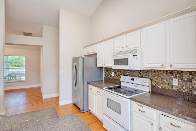 832 Willow Run St, Minneola, FL 34715 - kitchen with white appliances, light wood finished floors, dark countertops, and decorative backsplash