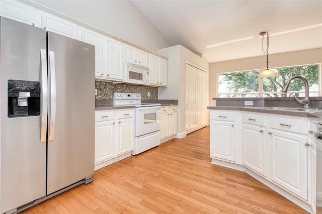 832 Willow Run St, Minneola, FL 34715 - kitchen with white appliances, vaulted ceiling, light wood-style flooring, tasteful backsplash, and white cabinets
