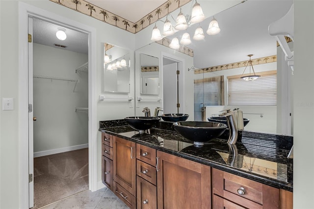 15916 Indian Wells Ct, Clermont, FL 34711 - bathroom featuring double vanity, a walk in closet, and baseboards
