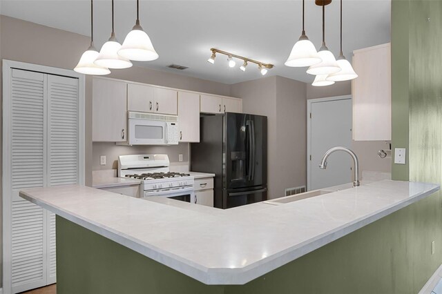 15916 Indian Wells Ct, Clermont, FL 34711 - kitchen featuring white appliances, a peninsula, a sink, light countertops, and white cabinets