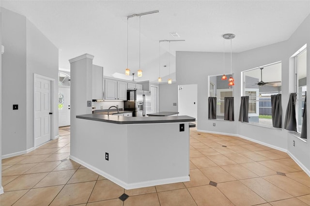 2705 Bayview Dr, Eustis, FL 32726 - kitchen with stainless steel refrigerator with ice dispenser, a ceiling fan, dark countertops, light tile patterned floors, and high vaulted ceiling
