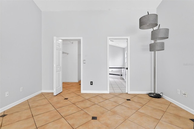 2705 Bayview Dr, Eustis, FL 32726 - unfurnished bedroom featuring light tile patterned floors, a walk in closet, baseboards, and ensuite bath