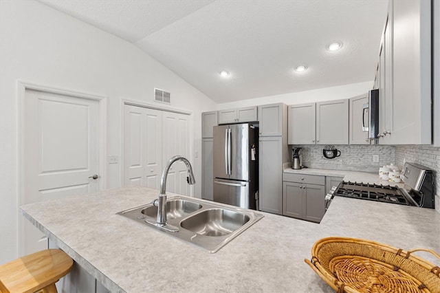 1225 Eunice St, The Villages, FL 34762 - kitchen with appliances with stainless steel finishes, a sink, vaulted ceiling, tasteful backsplash, and light countertops