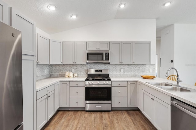 1225 Eunice St, The Villages, FL 34762 - kitchen featuring stainless steel appliances, a sink, vaulted ceiling, light countertops, and backsplash