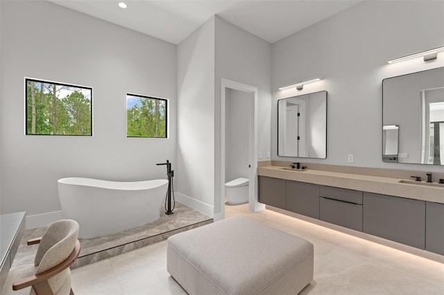16320 Pendio Dr, Bella Collina, FL 34756 - bathroom with double vanity, a freestanding bath, toilet, baseboards, and recessed lighting