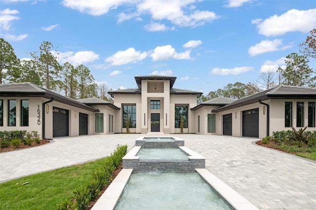 16320 Pendio Dr, Bella Collina, FL 34756 - prairie-style home featuring stucco siding, an attached garage, decorative driveway, and a pool with connected hot tub