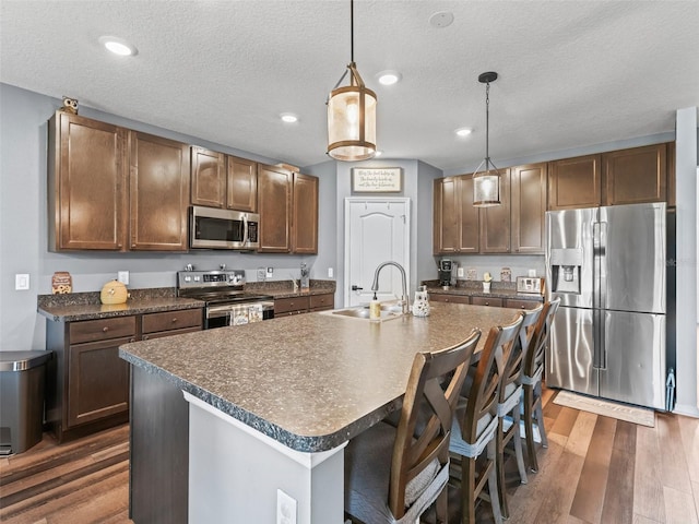 1824 Forest Glen Dr, Fruitland Park, FL 34731 - kitchen featuring appliances with stainless steel finishes, dark countertops, a sink, dark wood-style flooring, and a textured ceiling