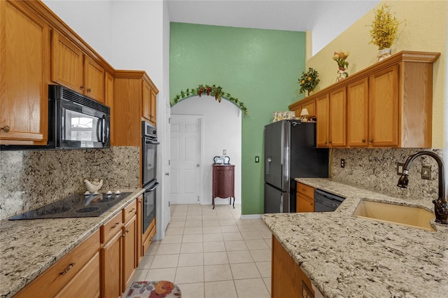 316 Dupont Cir, Howey In The Hills, FL 34737 - kitchen featuring black appliances, a sink, light tile patterned floors, backsplash, and a towering ceiling