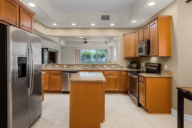 52 Camino Real Blvd, Howey In The Hills, FL 34737 - kitchen with appliances with stainless steel finishes, a raised ceiling, recessed lighting, a ceiling fan, and light stone counters