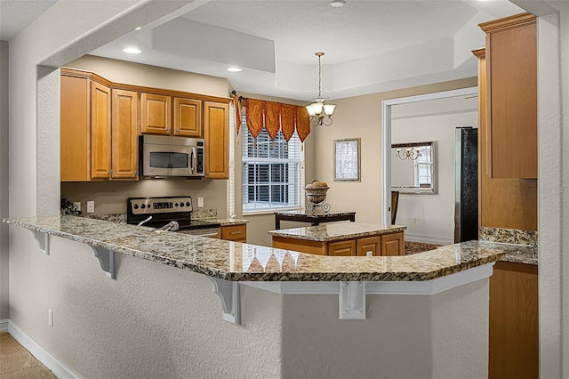 52 Camino Real Blvd, Howey In The Hills, FL 34737 - kitchen with stainless steel appliances, light stone counters, healthy amount of natural light, recessed lighting, and brown cabinets
