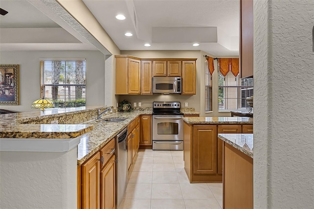 52 Camino Real Blvd, Howey In The Hills, FL 34737 - kitchen with stainless steel appliances, a sink, a raised ceiling, light stone countertops, and a peninsula