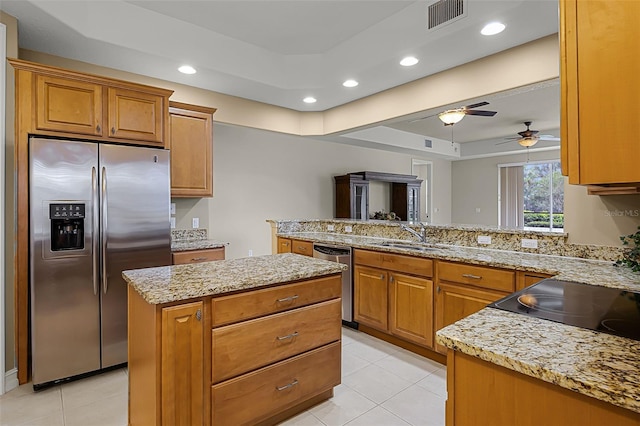52 Camino Real Blvd, Howey In The Hills, FL 34737 - kitchen with appliances with stainless steel finishes, a sink, a peninsula, brown cabinetry, and a raised ceiling
