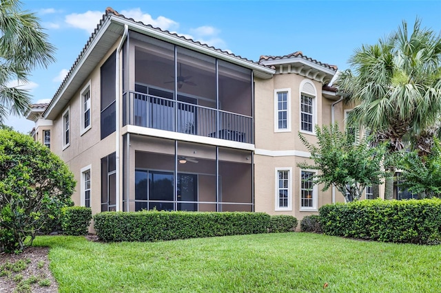 52 Camino Real Blvd, Howey In The Hills, FL 34737 - back of house with a sunroom, a ceiling fan, stucco siding, and a lawn