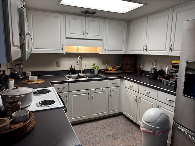 679 Ave Q SE, Winter Haven, FL 33880 - kitchen with dark countertops, stainless steel refrigerator with ice dispenser, white cabinets, light tile patterned floors, and electric stove