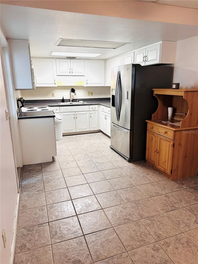 679 Ave Q SE, Winter Haven, FL 33880 - kitchen with dark countertops, white cabinetry, fridge with ice dispenser, and light tile patterned flooring
