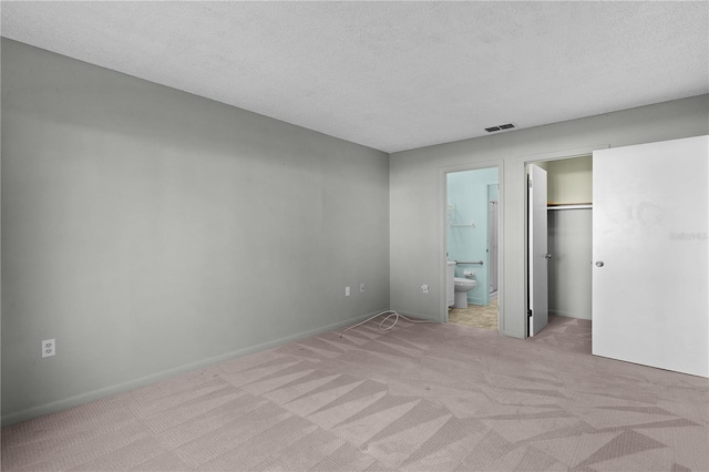 504 Silver Crse Unit A, Ocala, FL 34472 - unfurnished bedroom with light carpet, connected bathroom, a textured ceiling, a walk in closet, and a closet