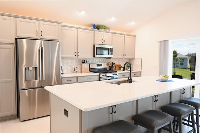 6301 Danielson Loop, The Villages, FL 32163 - kitchen with stainless steel appliances, tasteful backsplash, a kitchen island with sink, a breakfast bar, and vaulted ceiling