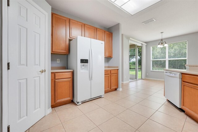 2745 Shearwater St, Clermont, FL 34711 - kitchen with white appliances, a chandelier, light countertops, hanging light fixtures, and light tile patterned floors