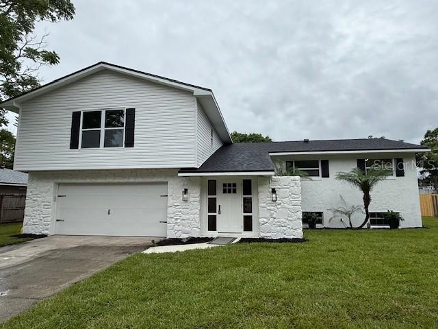 8203 Bluestar Cir, Orlando, FL 32819 - split level home with stone siding, a garage, and concrete driveway