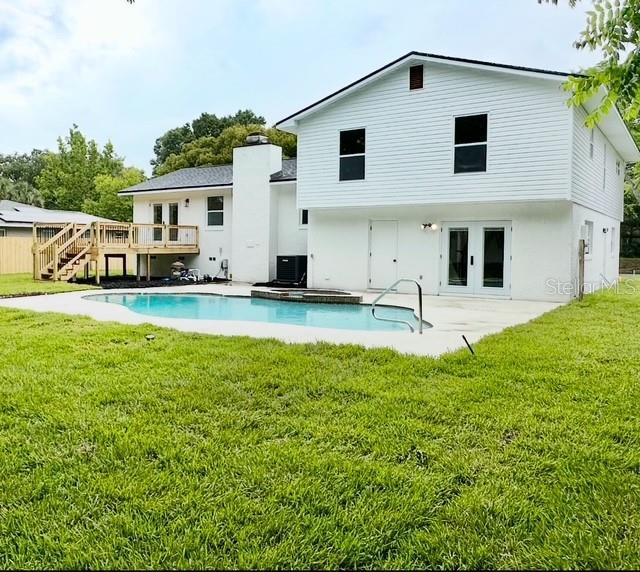 8203 Bluestar Cir, Orlando, FL 32819 - rear view of house featuring a wooden deck, french doors, an outdoor pool, a yard, and stairway