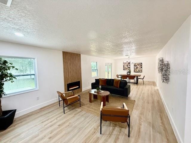 8203 Bluestar Cir, Orlando, FL 32819 - living area with a textured ceiling, light wood-style flooring, a chandelier, a fireplace, and baseboards