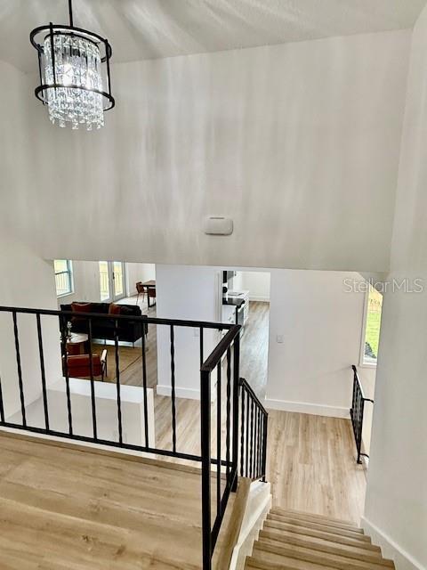 8203 Bluestar Cir, Orlando, FL 32819 - stairs featuring wood finished floors, baseboards, a chandelier, and healthy amount of natural light
