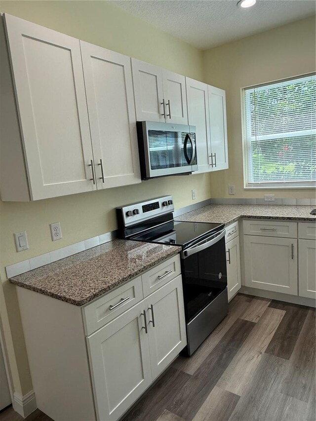 501 N Simpson St, Mount Dora, FL 32757 - kitchen with appliances with stainless steel finishes, dark wood-type flooring, white cabinetry, light stone countertops, and recessed lighting