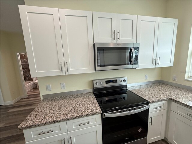 501 N Simpson St, Mount Dora, FL 32757 - kitchen featuring appliances with stainless steel finishes, white cabinets, dark wood-style flooring, and light stone countertops