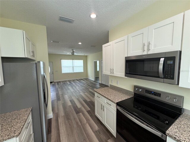 501 N Simpson St, Mount Dora, FL 32757 - kitchen with stainless steel appliances, dark wood finished floors, white cabinets, a ceiling fan, and open floor plan