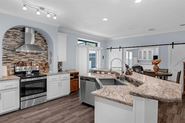 4048 Lake Griffin Rd, Lady Lake, FL 32159 - kitchen with appliances with stainless steel finishes, a sink, wall chimney exhaust hood, a barn door, and tasteful backsplash