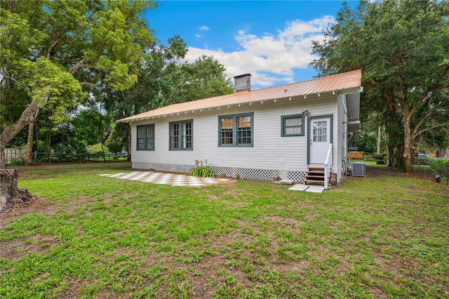 263 NE 1st St, Webster, FL 33597 - back of house featuring entry steps, central AC unit, a chimney, metal roof, and a patio