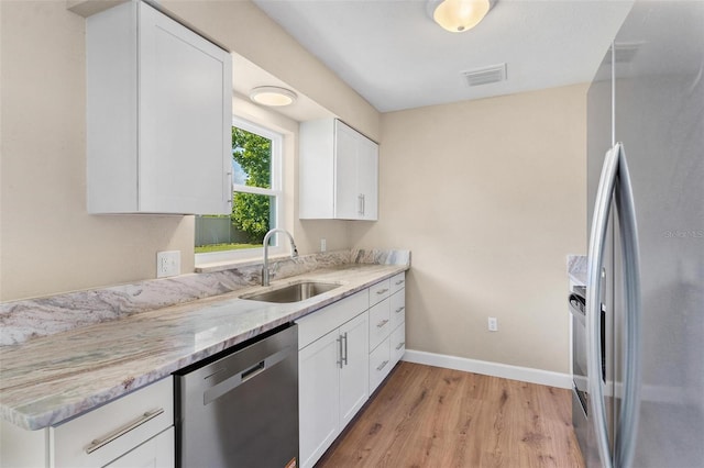 4 Kristin Ln, Eustis, FL 32726 - kitchen featuring appliances with stainless steel finishes, a sink, light wood-style floors, light stone countertops, and white cabinetry