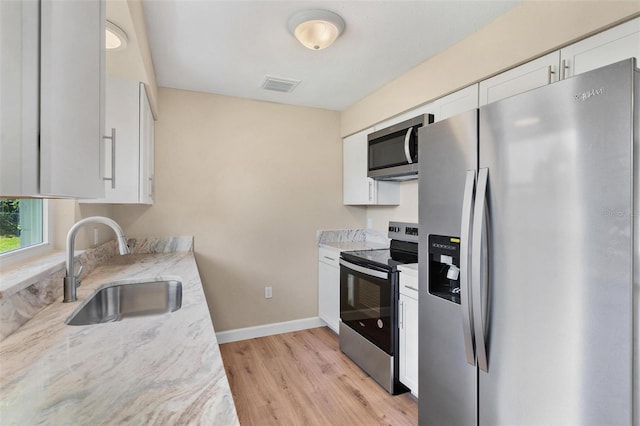4 Kristin Ln, Eustis, FL 32726 - kitchen with appliances with stainless steel finishes, a sink, light wood-type flooring, white cabinetry, and baseboards