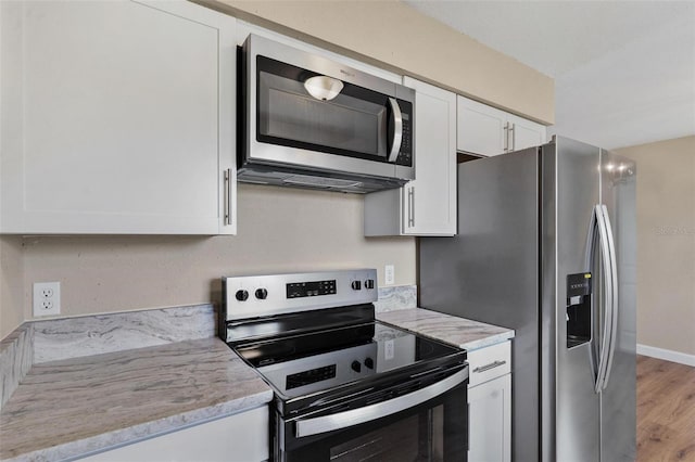 4 Kristin Ln, Eustis, FL 32726 - kitchen featuring appliances with stainless steel finishes, white cabinetry, light wood finished floors, and light stone countertops