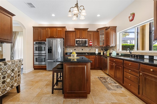 5144 Rishley Run Way, Mount Dora, FL 32757 - kitchen with stainless steel appliances, a sink, a breakfast bar area, decorative backsplash, and arched walkways