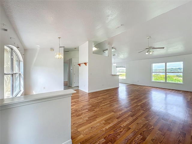 439 Gentle Breeze Dr, Minneola, FL 34715 - unfurnished living room with wood finished floors, ceiling fan, baseboards, a chandelier, and a textured ceiling