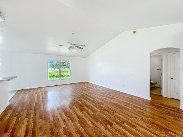 439 Gentle Breeze Dr, Minneola, FL 34715 - unfurnished living room with arched walkways, vaulted ceiling, a ceiling fan, wood finished floors, and baseboards