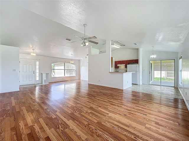 439 Gentle Breeze Dr, Minneola, FL 34715 - unfurnished living room with healthy amount of natural light, light wood-style flooring, ceiling fan, a textured ceiling, and high vaulted ceiling