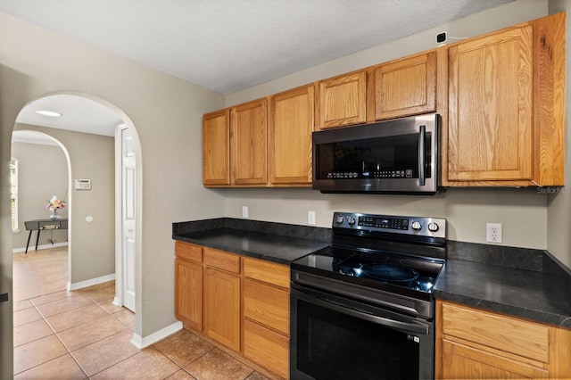 800 Daybreak Dr, Fruitland Park, FL 34731 - kitchen with black electric range, light tile patterned flooring, arched walkways, and dark countertops