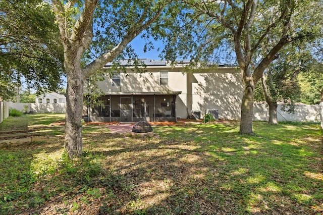 800 Daybreak Dr, Fruitland Park, FL 34731 - rear view of house with a sunroom, a fire pit, a fenced backyard, solar panels, and stucco siding