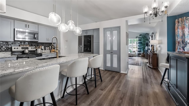 1130 Woodsong Way, Clermont, FL 34714 - kitchen with stainless steel appliances, a sink, gray cabinets, a chandelier, and light stone counters
