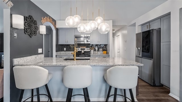 1130 Woodsong Way, Clermont, FL 34714 - kitchen featuring stainless steel appliances, a peninsula, light stone counters, a breakfast bar, and backsplash
