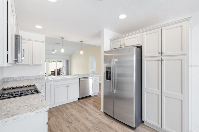 4157 Tiedemann Loop, The Villages, FL 32163 - kitchen with stainless steel appliances, a sink, light wood finished floors, white cabinetry, and light countertops