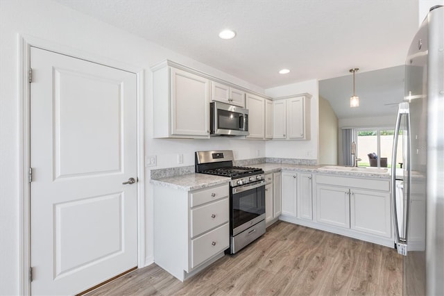 4157 Tiedemann Loop, The Villages, FL 32163 - kitchen featuring stainless steel appliances, light wood finished floors, a sink, recessed lighting, and decorative light fixtures